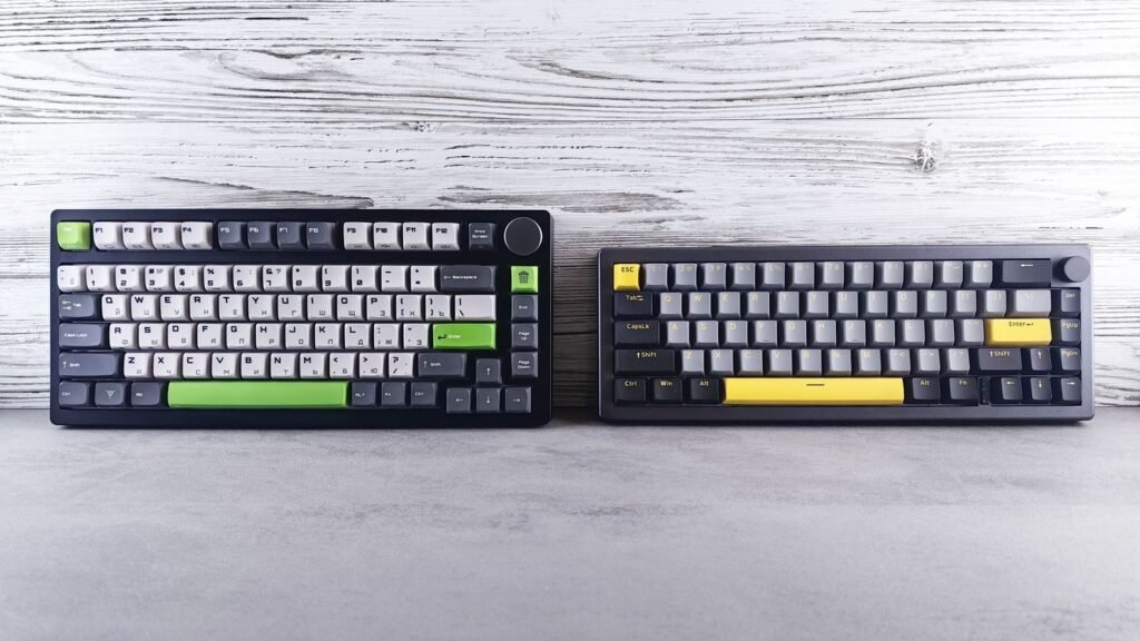 Two compact mechanical keyboards side by side on a gray surface against a white wooden wall, one 75% and one 65%