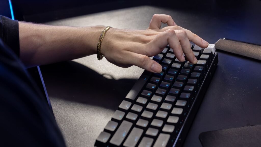 A hand typing on a compact black one-piece mechanical keyboard with the wrist angled toward the keys
