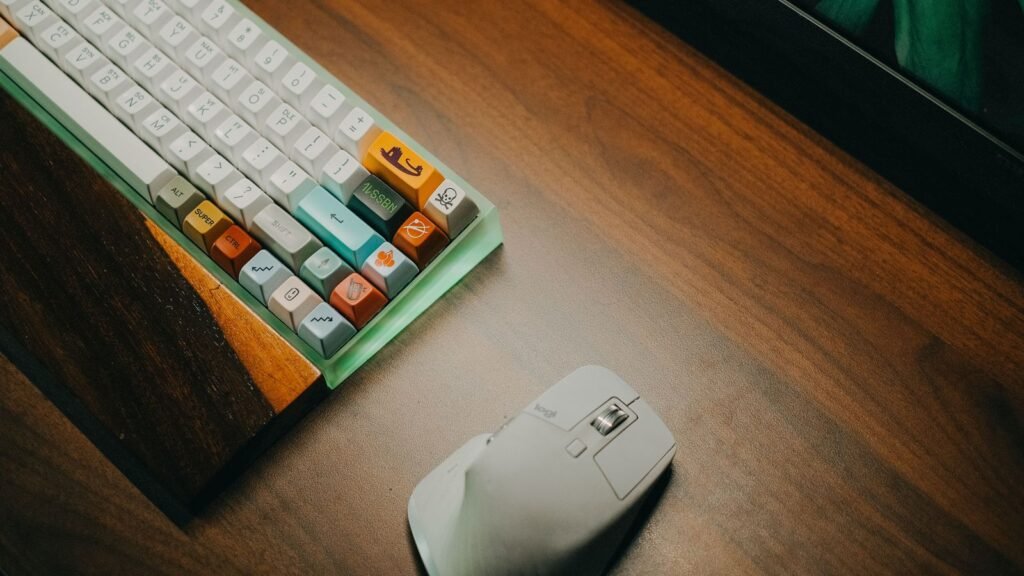 Corner of a compact mechanical keyboard with a frosted green case and colorful keycaps beside a white mouse on a wooden desk