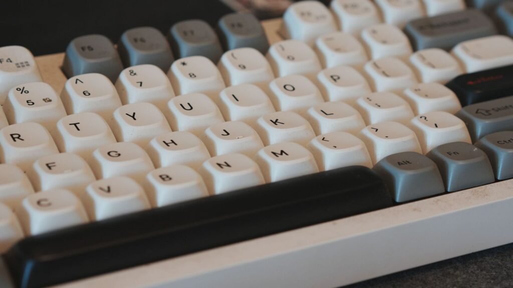 Close-up of white and gray sculpted keycaps on a mechanical keyboard with a black spacebar