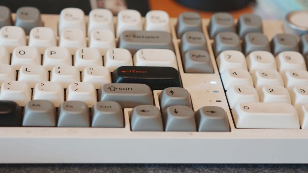 Close side view of a white and gray mechanical keyboard with tall, sculpted keycaps